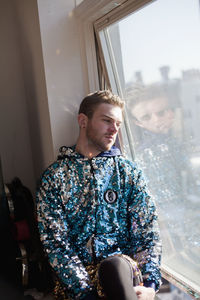 Young man looking through window