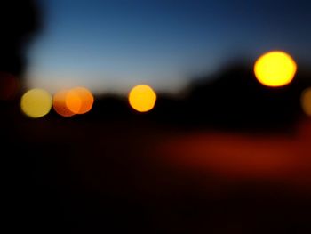 Defocused image of illuminated lights against sky at night