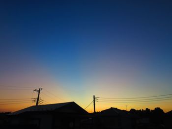 Silhouette houses against sky during sunset