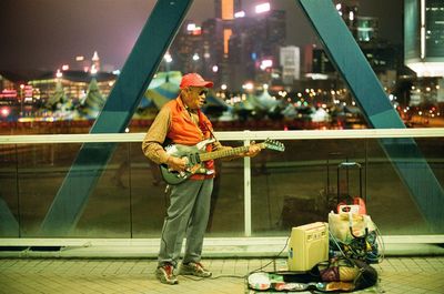 Full length of man standing on illuminated city at night