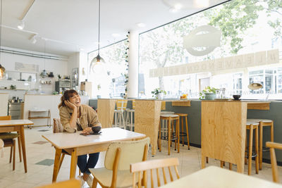 Young woman sitting on table in cafe