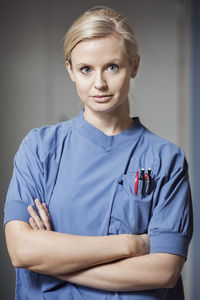 Portrait of young woman standing against wall