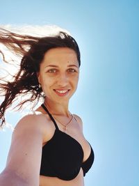 Portrait of smiling young woman against sky