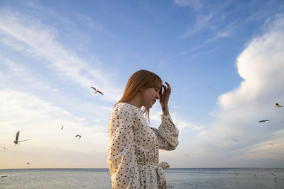 Woman standing at beach against sky