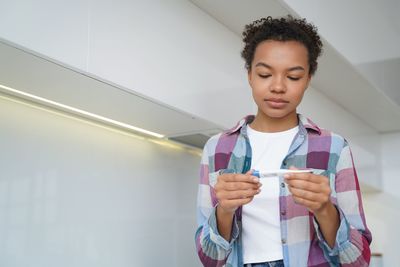 Portrait of young woman standing against wall