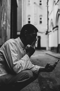 Side view of man using mobile phone on street