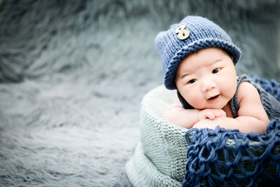 Close-up of cute baby boy lying down in basket on rug