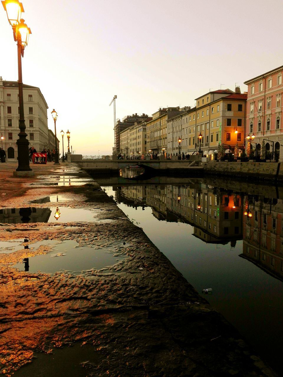 RIVER BY ILLUMINATED BUILDINGS AGAINST SKY DURING SUNSET