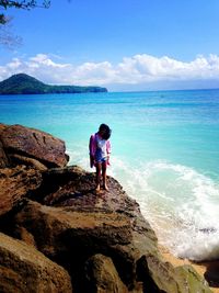 Rear view of boy looking at sea against sky