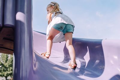 Full length of girl playing on slide against sky