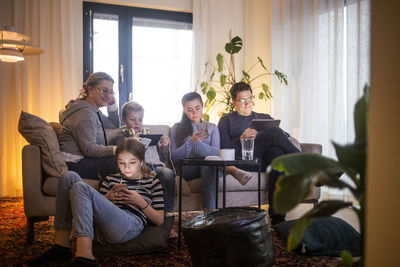 Family using wireless technologies in living room while relaxing on sofa at modern home