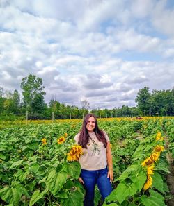 Portrait of young woman standing on field against sky