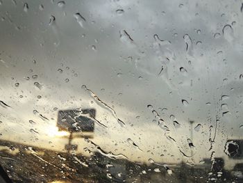 Raindrops on window against sky