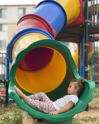 Full length of cute girl sitting on slide at playground