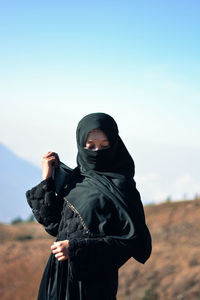 Young woman wearing burka while standing on field against sky