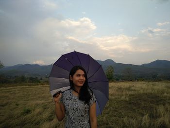 Young woman smiling while standing on land against sky