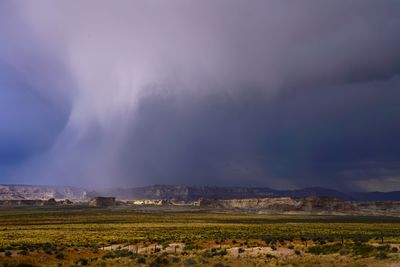 Scenic view of field against storm clouds