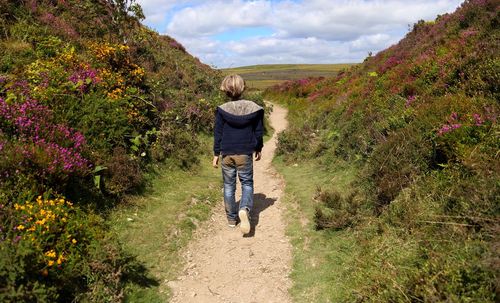 Full length of boy on flowers against sky