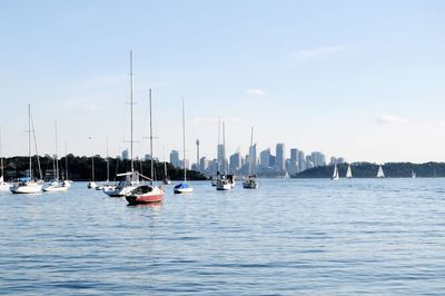 Sailboats moored in sea against sky