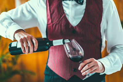 Midsection of man pouring wine in wineglass