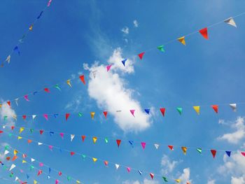 Colorful triangle flags on ropes, symbol of event and joyful, with bright blue sky background.
