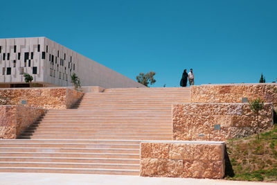 Staircase against building against clear blue sky