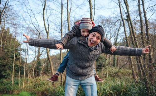 Full length of father and daughter on tree at park