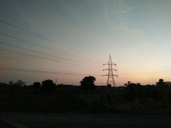 Silhouette of electricity pylons on countryside landscape