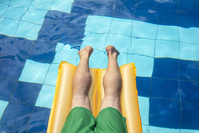 Low section of man relaxing in swimming pool