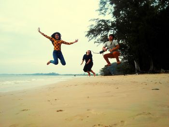 Full length of friends jumping on beach