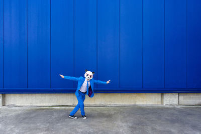 Full length of woman standing against blue wall