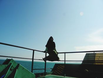 Low angle view of woman standing against sea