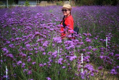 Full length of woman with purple flowers on field