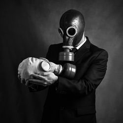 Businessman wearing gas mask while standing against wall