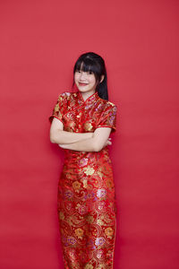 Portrait of a smiling young woman against red background