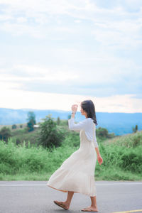 Woman standing on road against sky