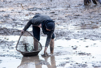 Woman fishing in a muddy pond