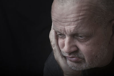 Close-up of mature man against black background