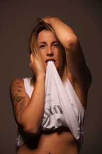 Portrait of young woman standing against black background