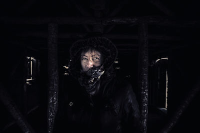 Portrait of woman hooded jacket in darkroom