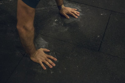 Cropped hands of man doing push-ups on floor at gym