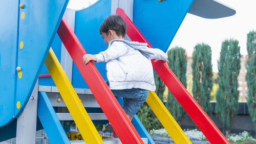 Rear view of boy on slide at playground