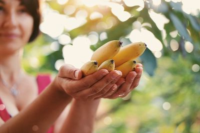 Woman holding bananas while standing outdoors