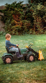 Side view of a boy playing with toy tractor