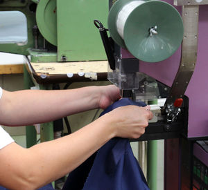 Midsection of tailor using sewing machine while stitching textile