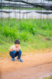 Full length of boy crouching on land