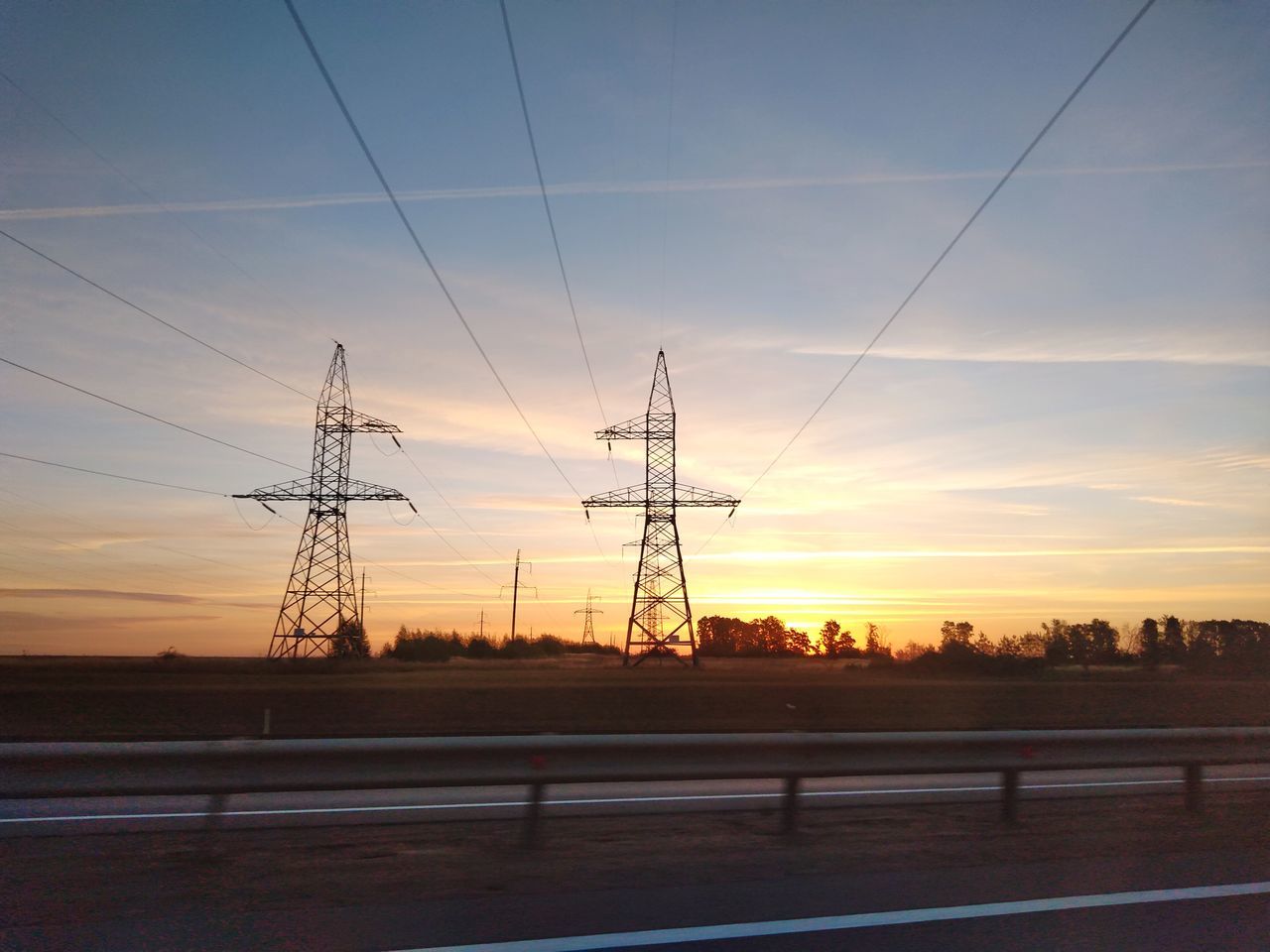 ELECTRICITY PYLON ON FIELD AGAINST SKY AT SUNSET