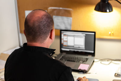 Rear view of man using laptop