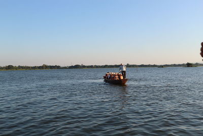 People on boat in sea against clear sky