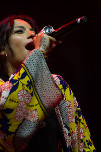 Low angle view of woman singing against black background